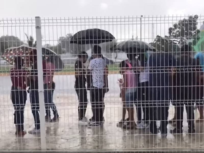 Padres e hijos esperan la vacuna bajo la lluvia en Cancún