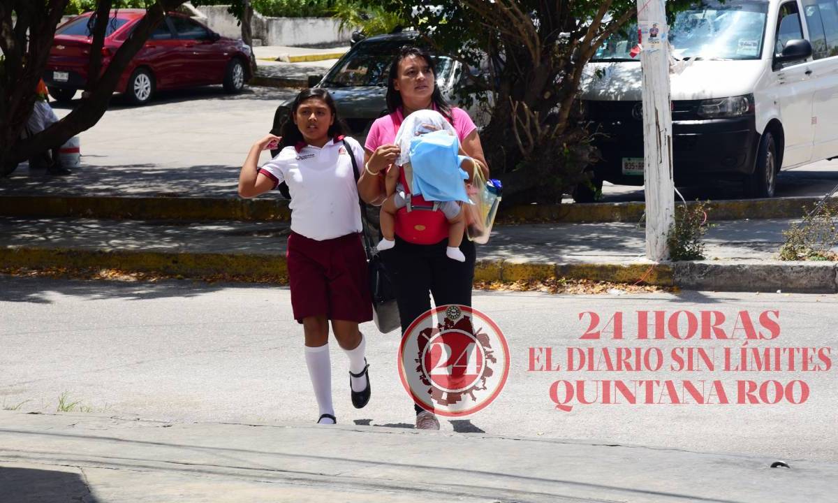 Madre de familia cruza una avenida con sus hijos, en Cancún.