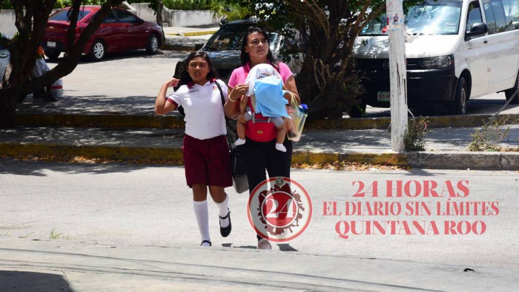 Madre de familia cruza una avenida con sus hijos, en Cancún.
