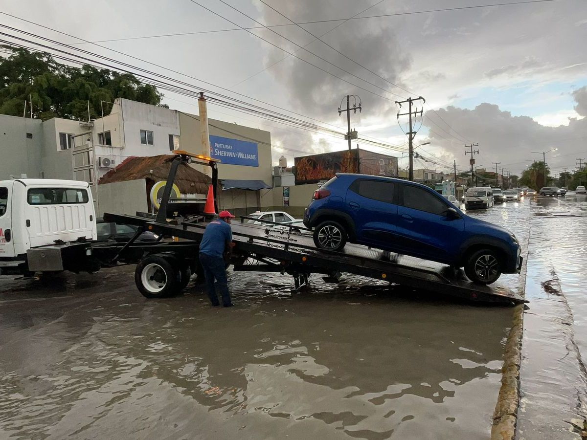Una grúa retira un vehículo varado en un encharcamiento en Cancún.