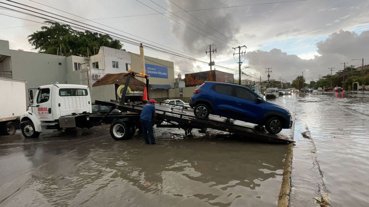 Una grúa retira un vehículo varado en un encharcamiento en Cancún.
