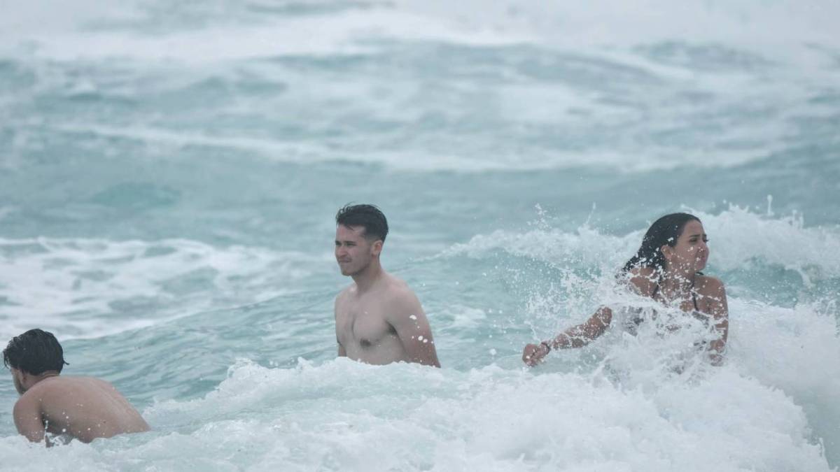 Bañistas en una playa mientras llueve.