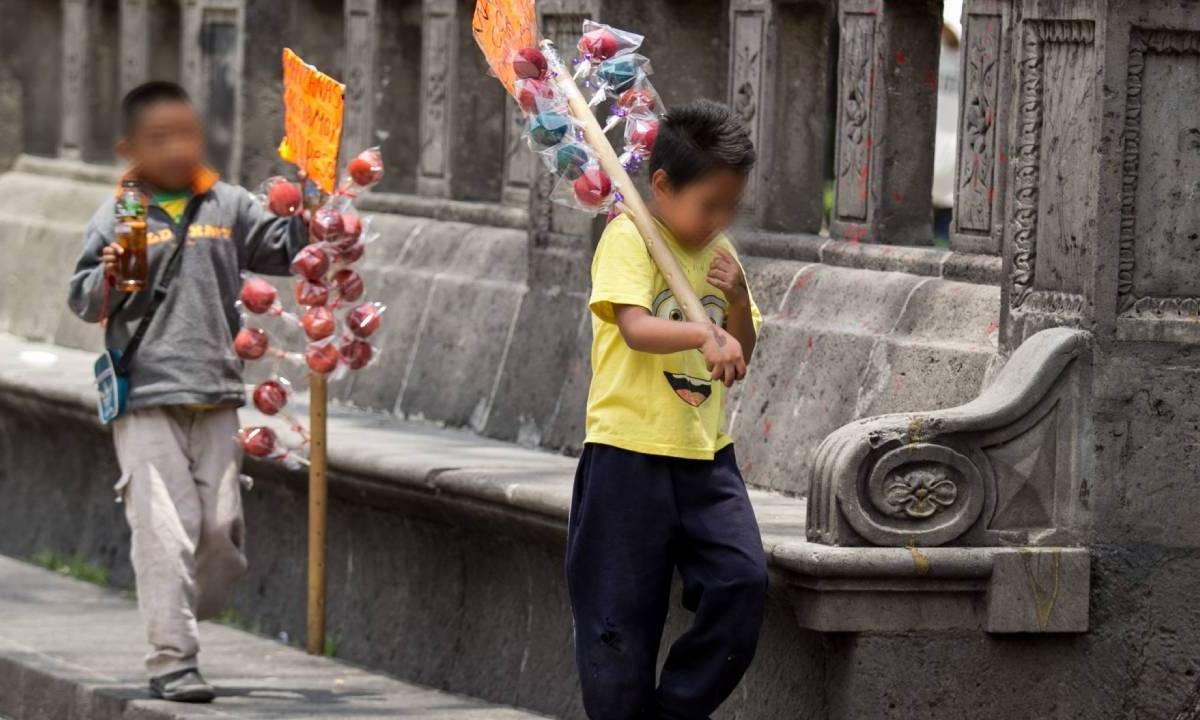 Dos niños venden manzanas con chamoy en una calle de México.