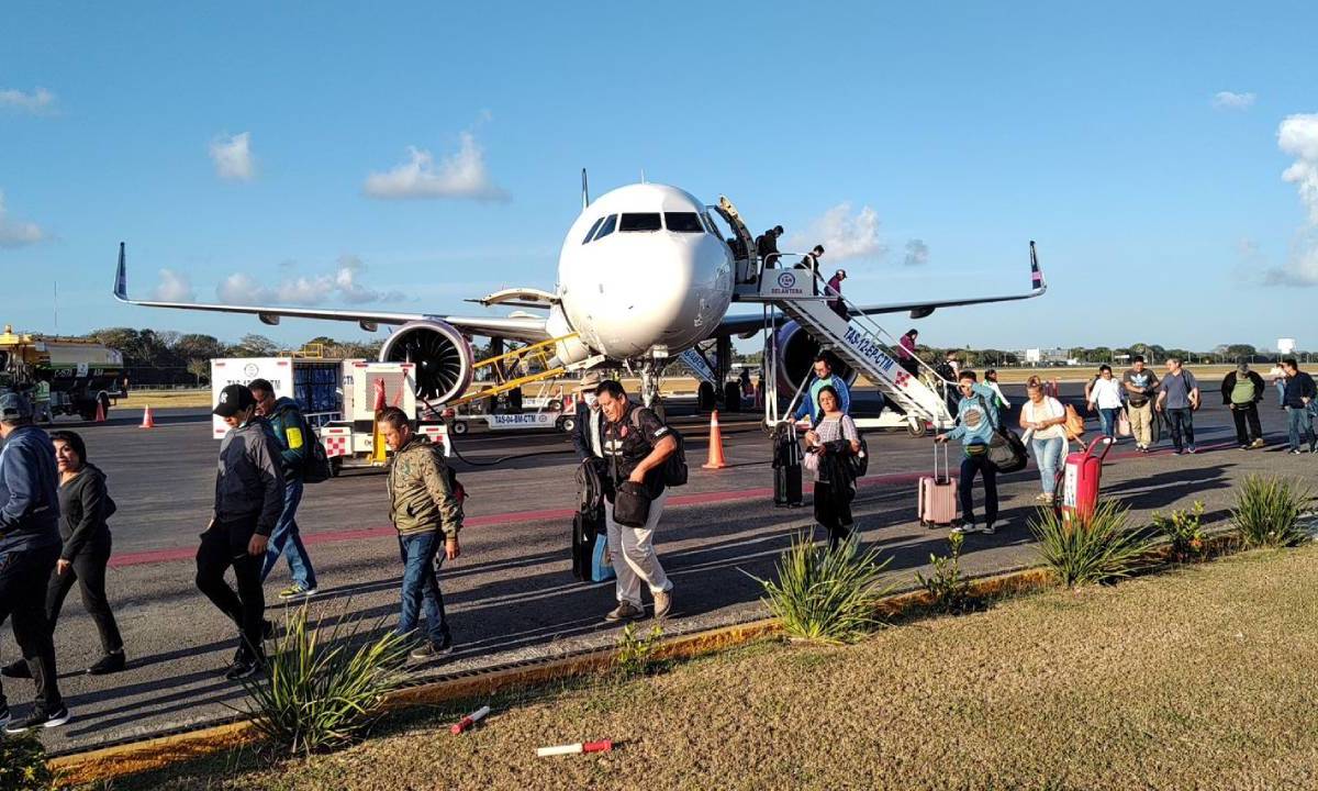 Turistas bajan del avión en Cancún.