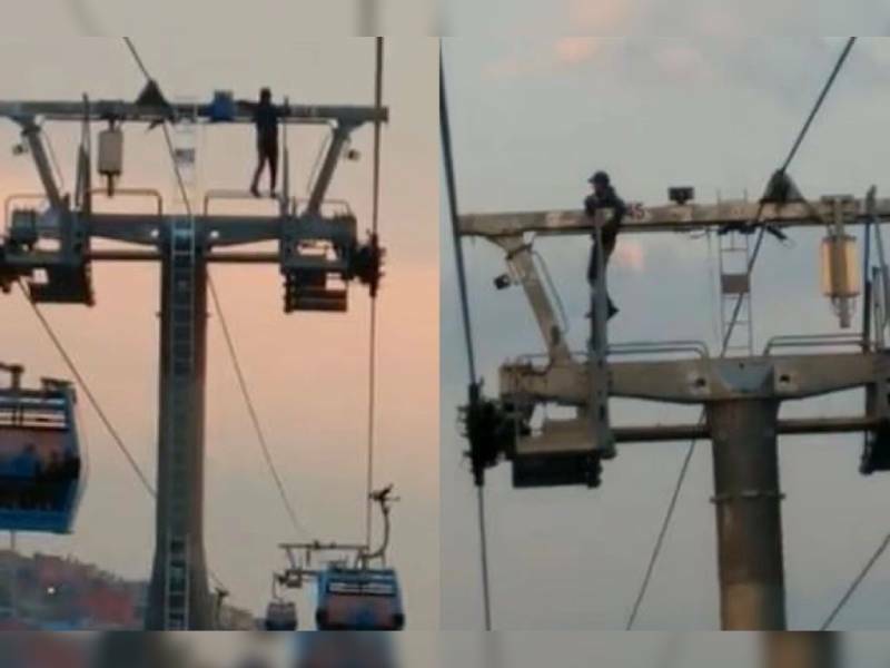Hombre escala a lo alto de una torre del Cablebús