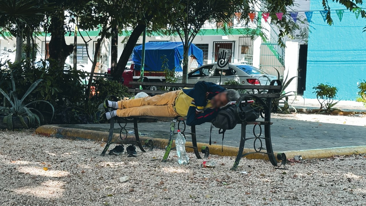 Persona duerme en un parque de Cancún.